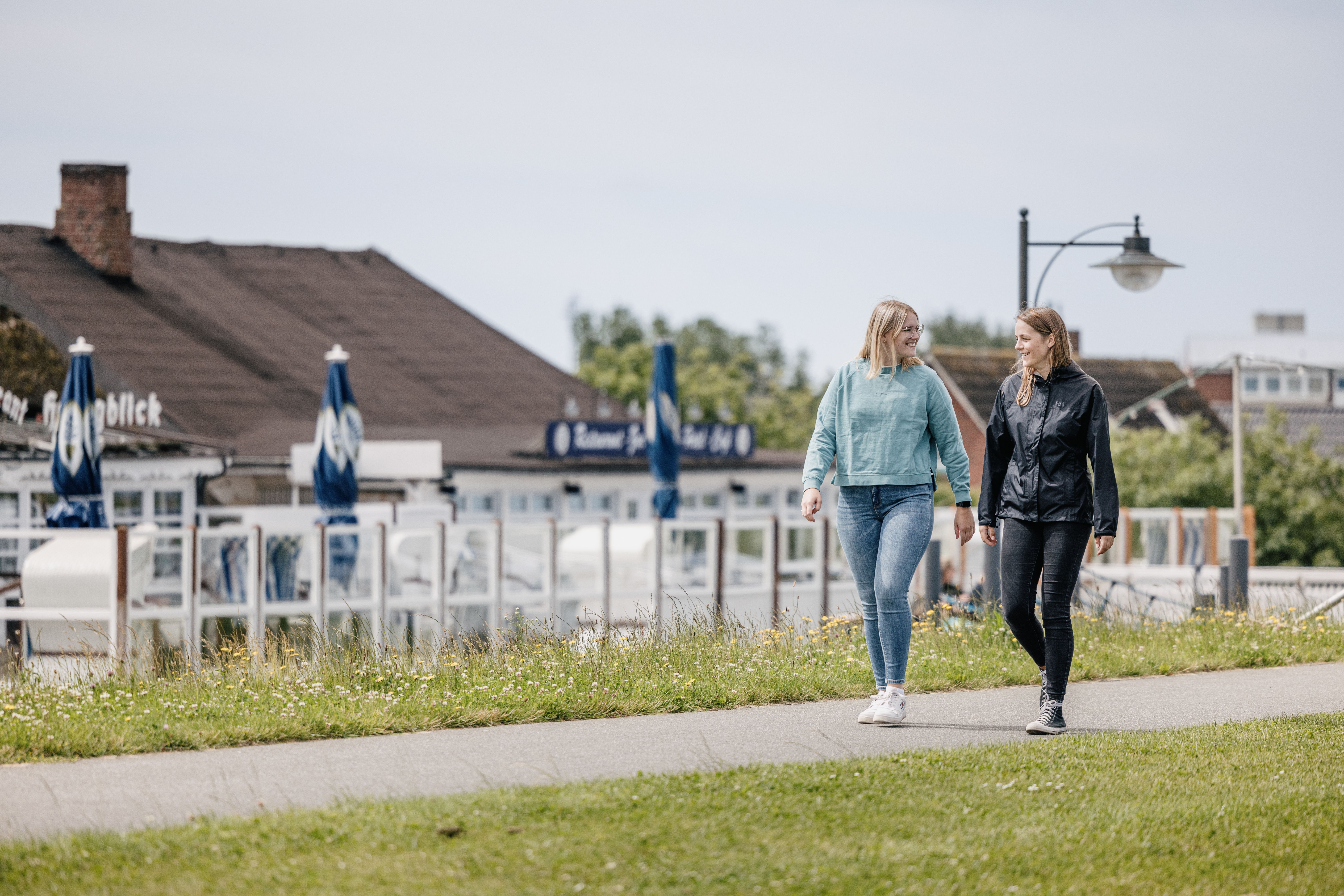 Spaziergängerinnen auf Deich vor Hotel auf Nordstrand